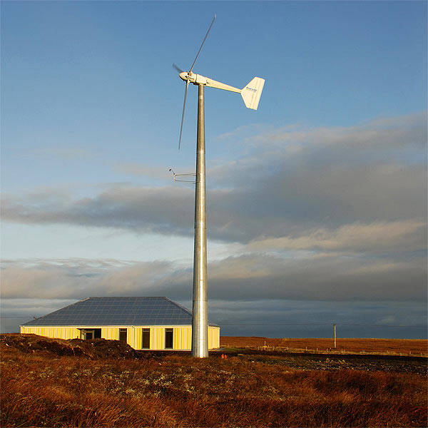 View of the completed building showing the 20kW wind turbine in the foreground which supplies electricity to the building and an electric car for use by the Trust